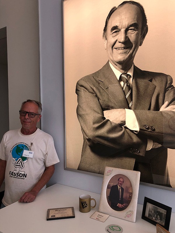 Tim Kmetz poses in front of a photo of his father, Avery Dennison employee John Kmetz (table) and Avery Dennison Founder, Stanton "Stan" Avery (wall).